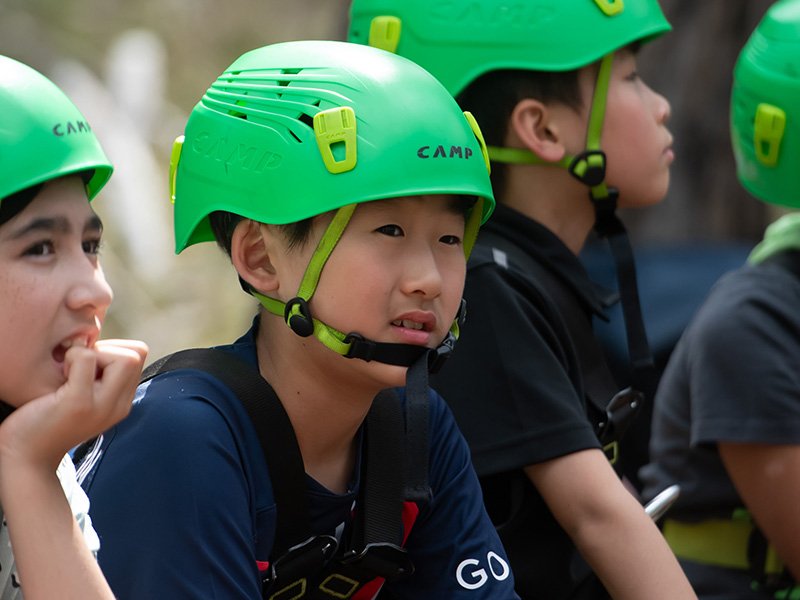 Group of primary students wearing helmets for a climbing activity.
