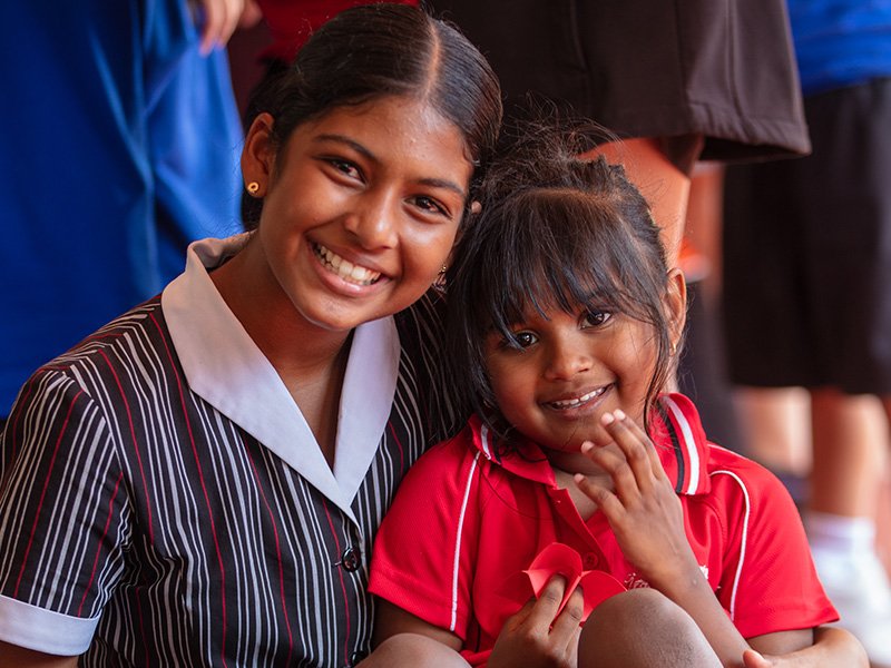 High school student smiling with primary student.