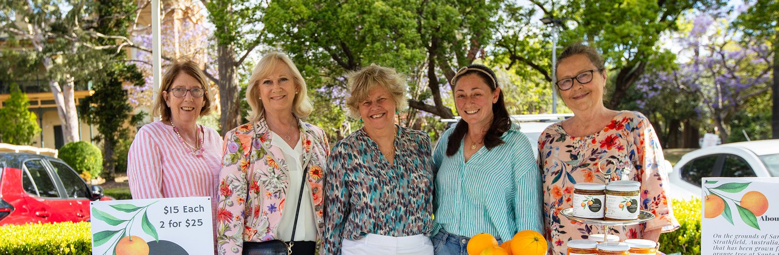 Ex-students standing and smiling at a market stall.