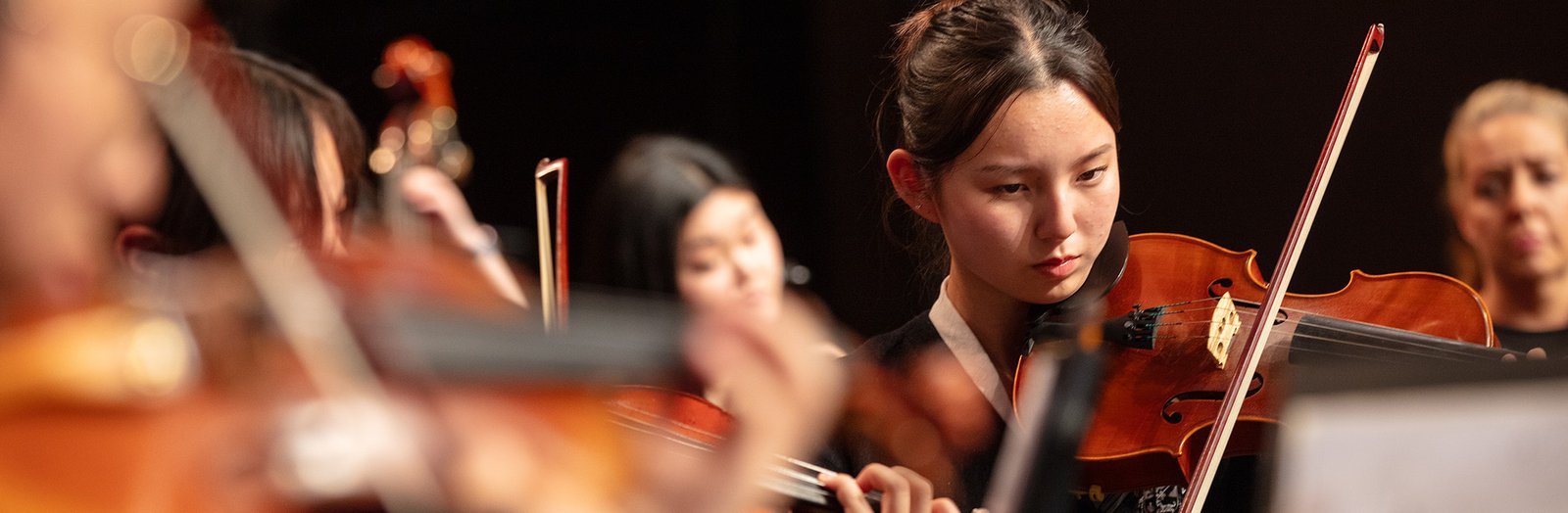 High school students playing string instruments in the orchestra.