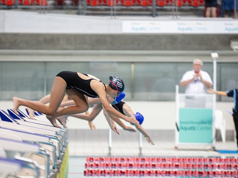 Group of high school students diving into pool.