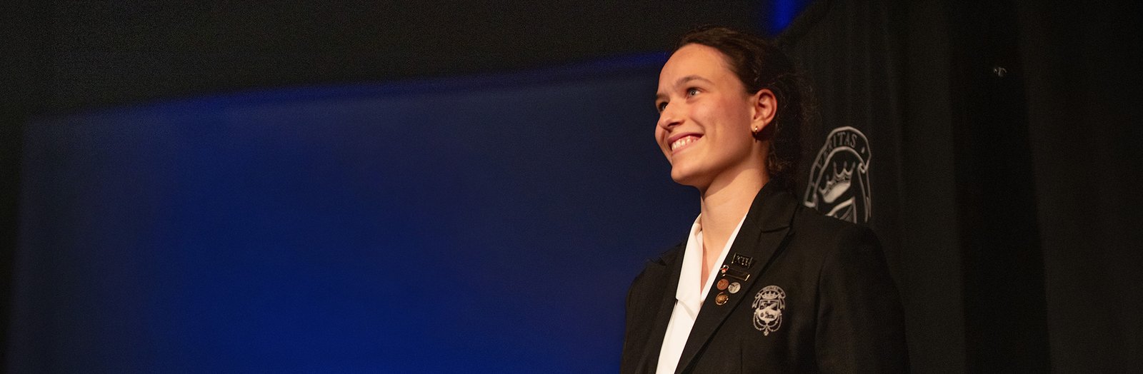 High school student standing on stage, smiling.