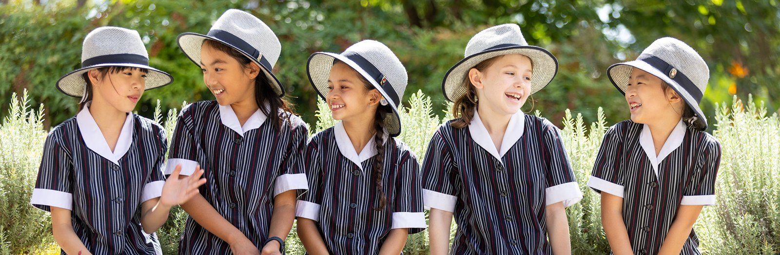 Group of five primary students sitting together outside chatting.