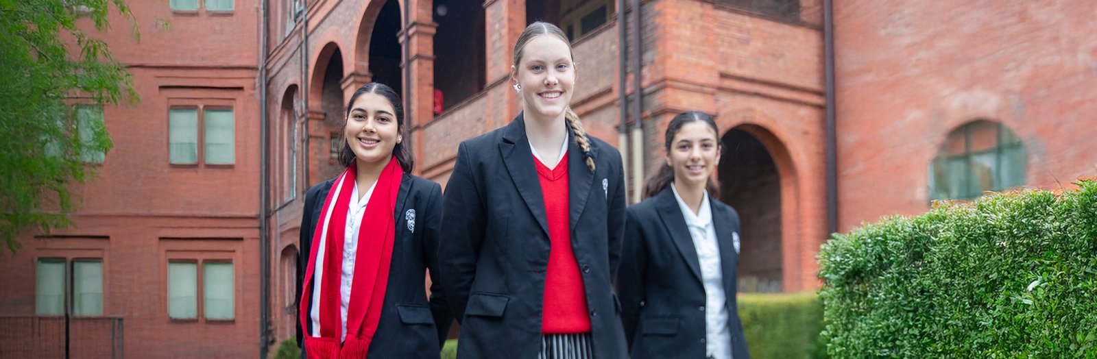Three high school students smiling and wearing variations of Santa Sabina College uniform.