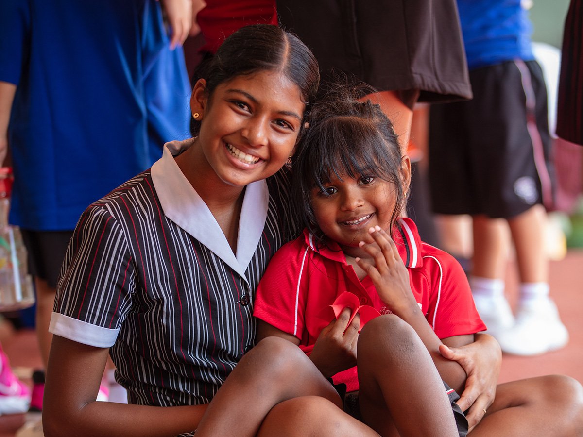 High school student smiling with a primary student.