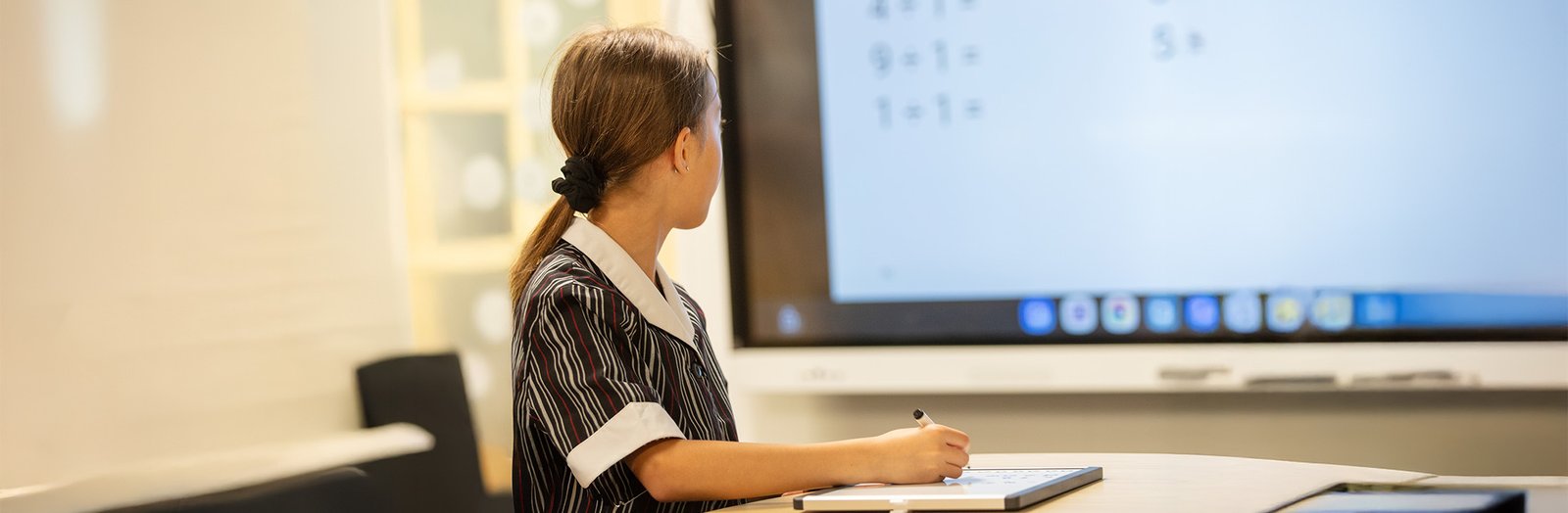 Student drawing on a whiteboard, solving a maths problem.