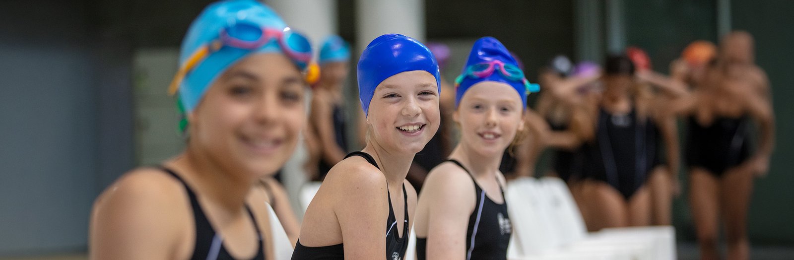 Students smiling, wearing swimming uniforms for the sports carnival.