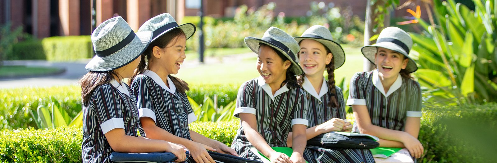 Group of students sitting next to a garden bed, smiling.
