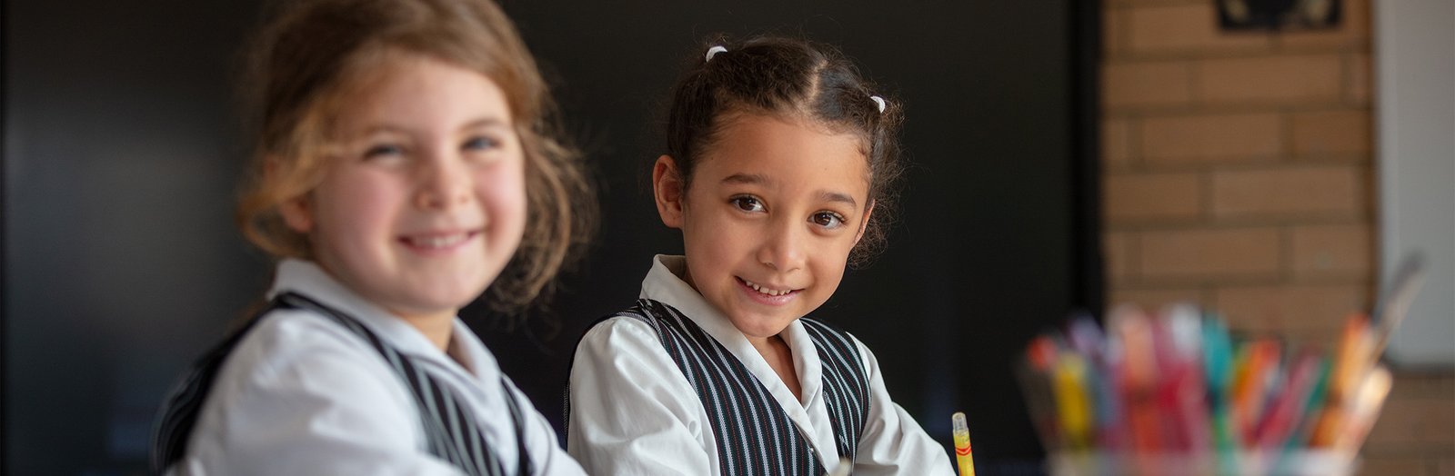 Two primary students in class, smiling.